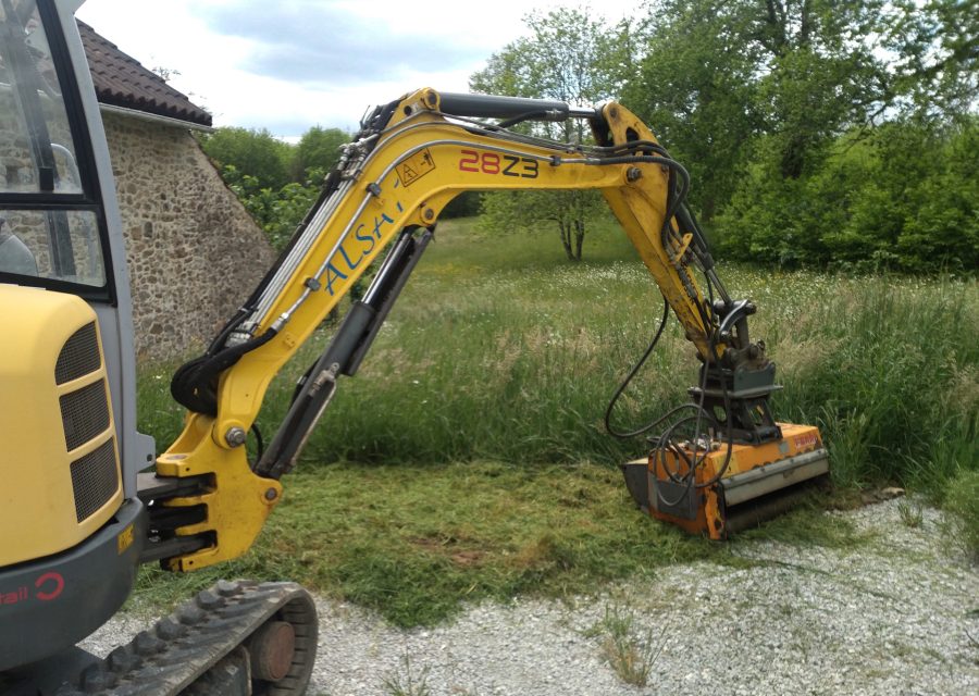 Mini-pelle équipée d'un broyeur, herbe haute broyée en bordure de parcelle